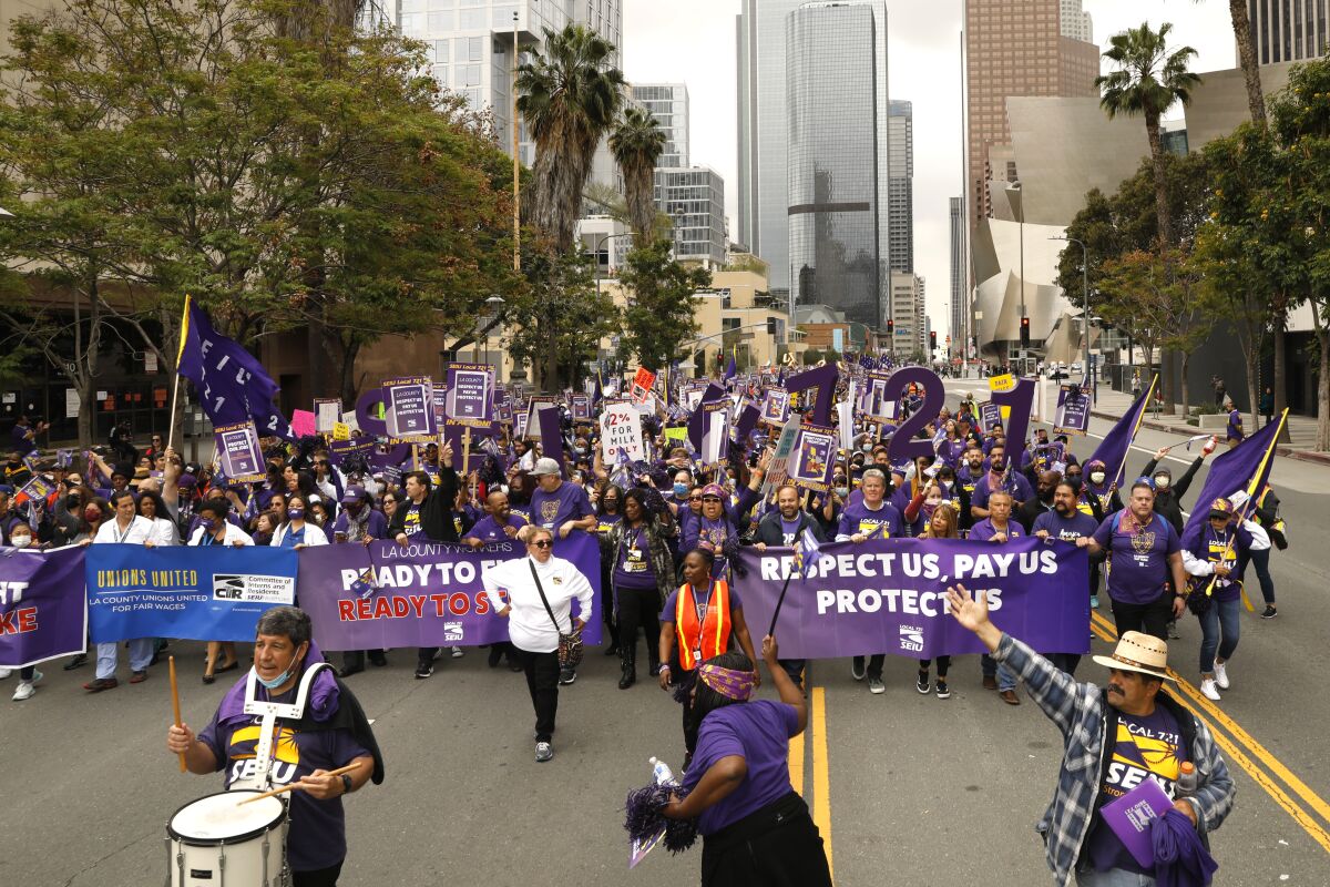 People, many in purple, march in a street.