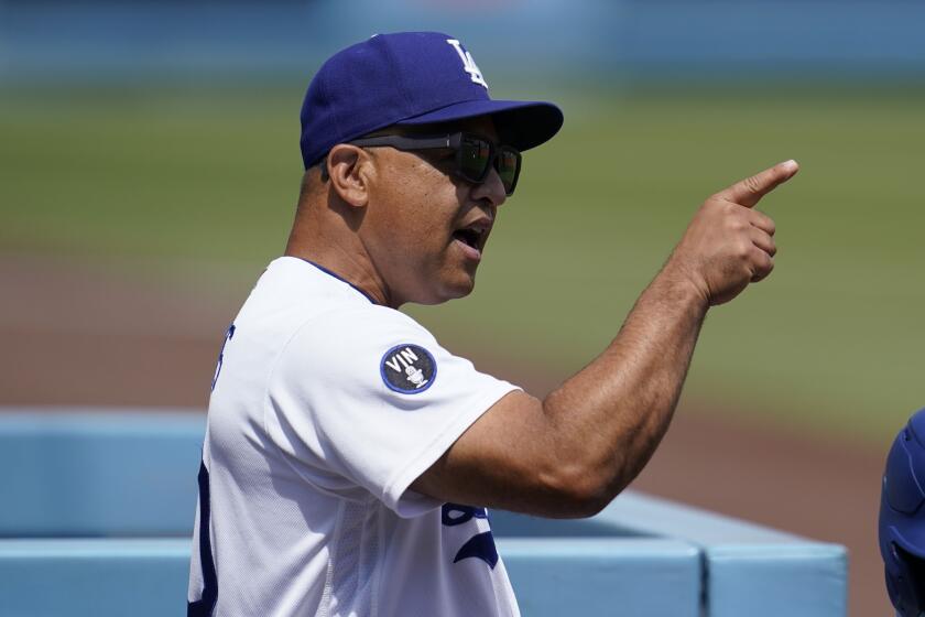 Los Angeles Dodgers manager Dave Roberts points in the dugout before a baseball game.