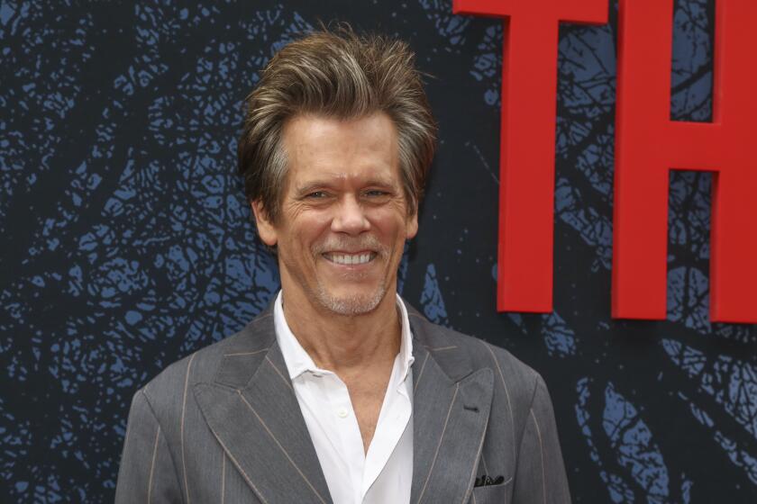 A man with gray-ish blond hair smiling and wearing a gray pinstripe suit