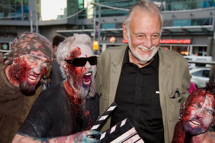 FILE - In this Sept. 12, 2009, file photo, director George Romero poses with some fans dressed as zombies after accepting a special award during the Toronto International Film Festival in Toronto. Romero, whose classic "Night of the Living Dead" and other horror films turned zombie movies into social commentaries and who saw his flesh-devouring undead spawn countless imitators, remakes and homages, has died. He was 77. Romero died Sunday, July 16, 2017, following a battle with lung cancer, said his family in a statement provided by his manager Chris Roe. (Darren Calabrese/The Canadian Press via AP, File)