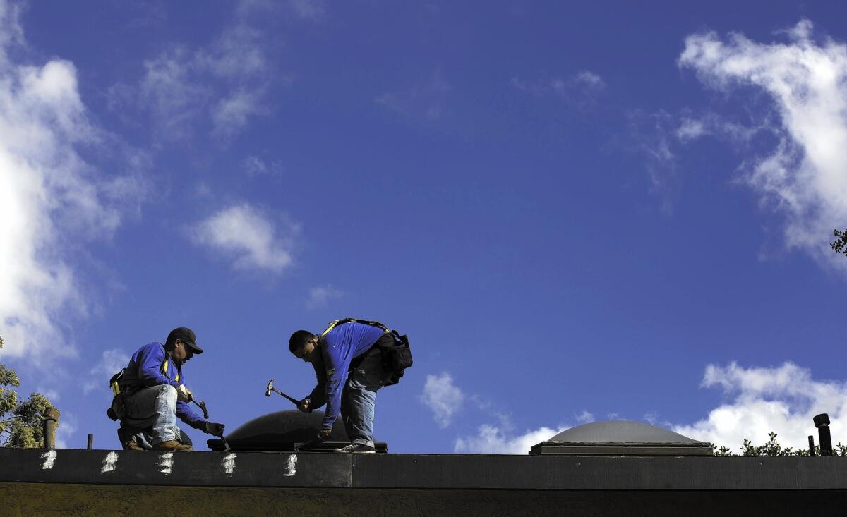 The National Weather Service has predicted that the area from San Diego to Los Angeles has a 60% to 69% chance of “above normal precipitation” this winter because of the El Ni?o weather phenomenon. Above, roofers at a condo complex in Lakewood.