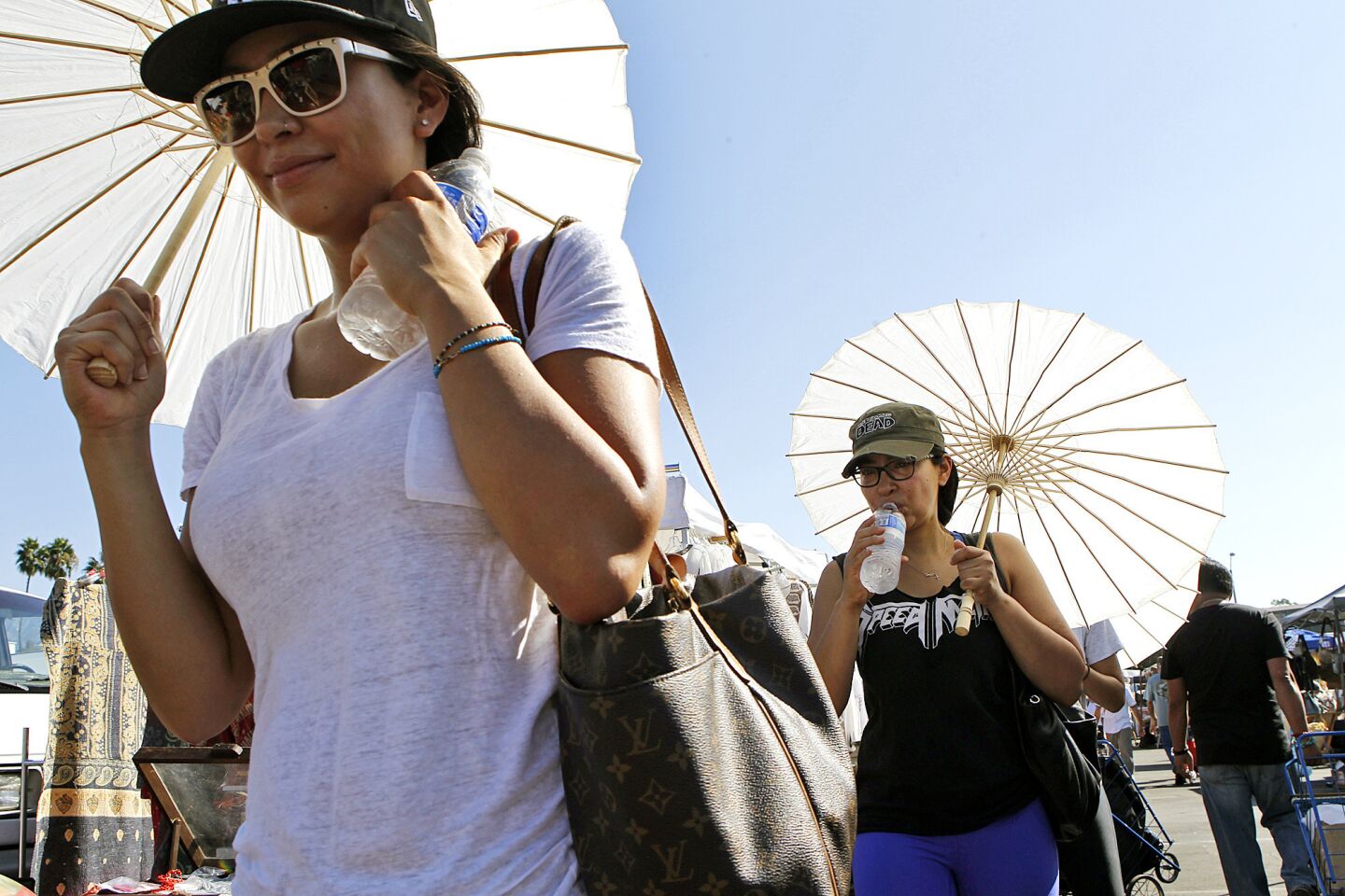 Sandra Figueroa, left, and her sister Elizabeth try to beat the heat at the Rose Bowl in Pasadena while shopping at the monthly flea market on Sunday.
