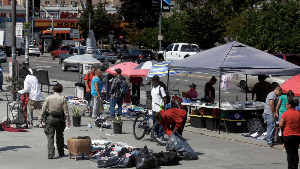 A sheriff's deputy has homeless street vendors pack up their wares along Alvarado Street in Westlake.