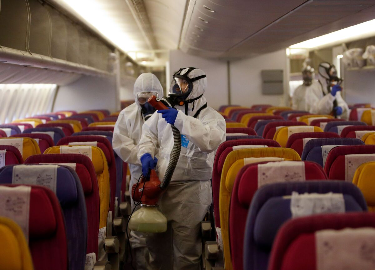 Technicians spray disinfectant on an airplane in Thailand