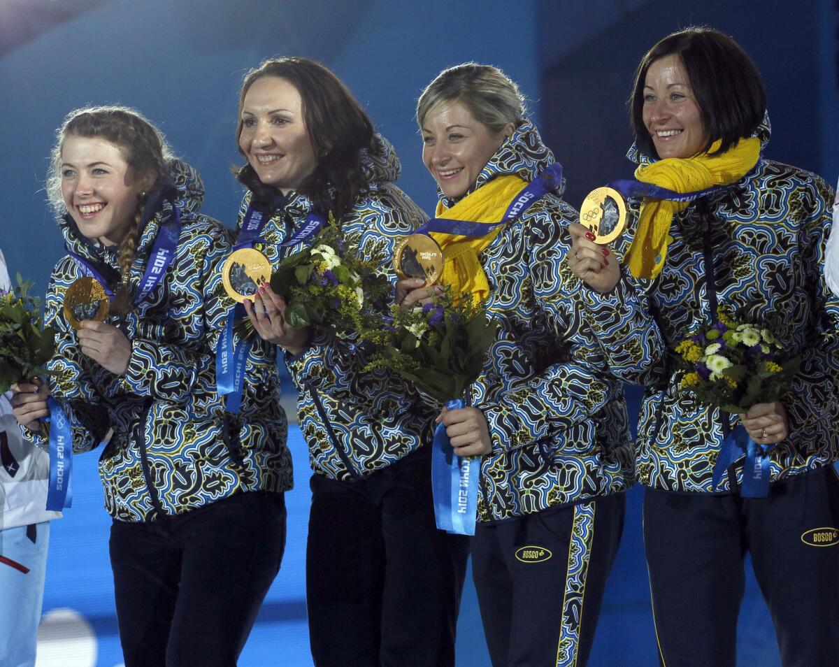 Members of the Ukrainian biathlon women's relay team hold up their gold medals inside the Olympic Park in Sochi, Russia.