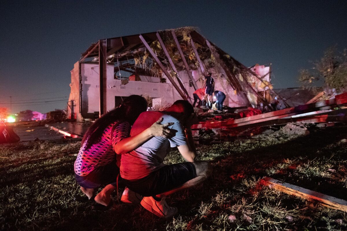 Henry Ramirez, a member of Primera Iglesia Dallas, is consoled by his mother, Maribel Morales, on Sunday as they survey severe damage to Primeria Iglesia Dallas, where Ramirez plays drums and Morales also attends, after a tornado tore through north Dallas.