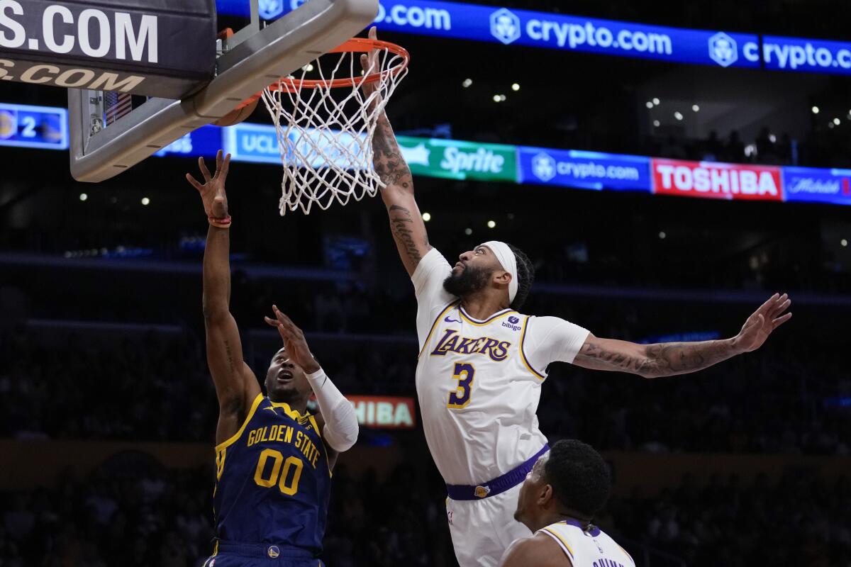 Golden State Warriors forward Jonathan Kuminga, left, shoots in front of Lakers forward Anthony Davis.