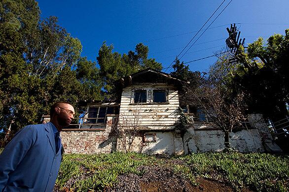 Dr. David R. Nelson, medical director of Barlow Respiratory Hospital, passes an old patient cottage on the facilitys grounds. The 106-year-old center sits on 25 acres two miles north of downtown.