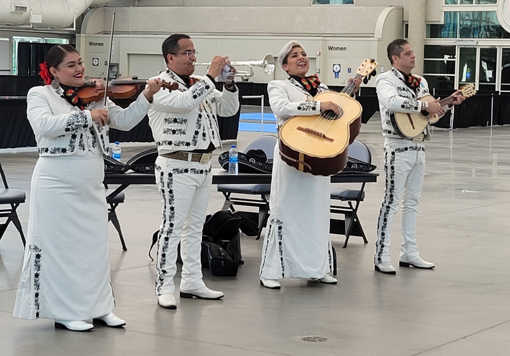 Four musicians dressed in white play mariachi music