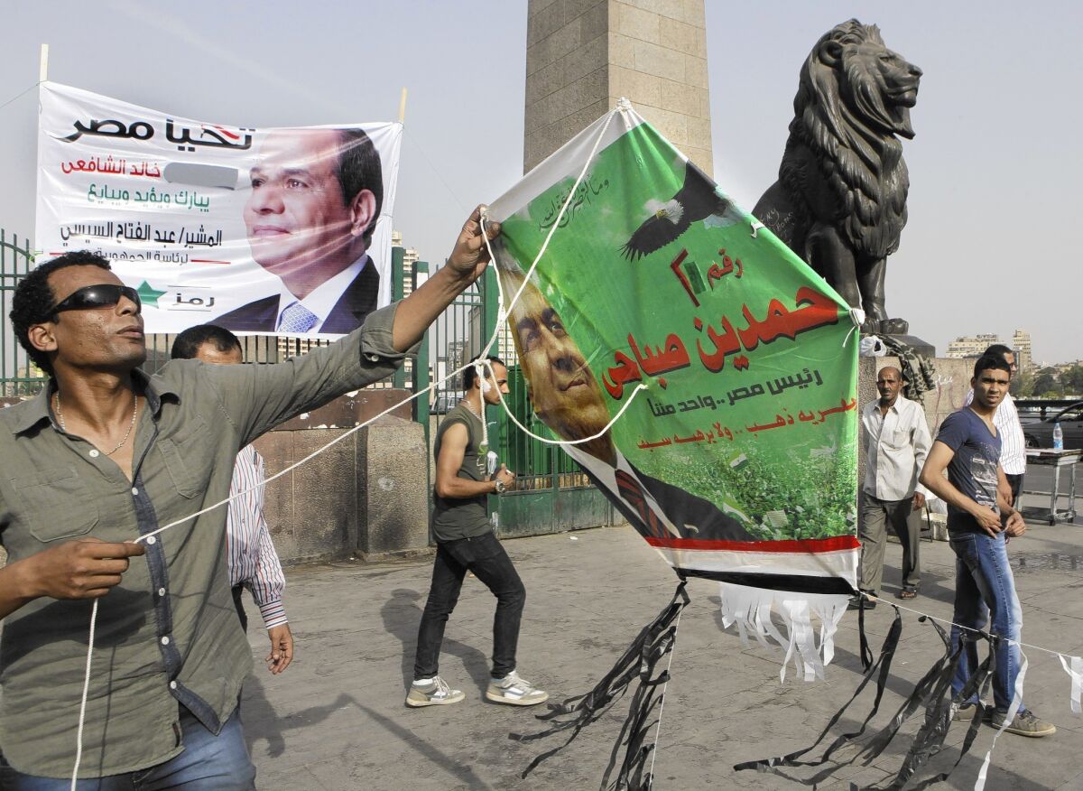 A supporter holds a kite bearing the image of presidential hopeful Hamdeen Sabahi during a rally on a Cairo bridge, where a banner for candidate and former Field Marshal Abdel Fattah Sisi has been erected.