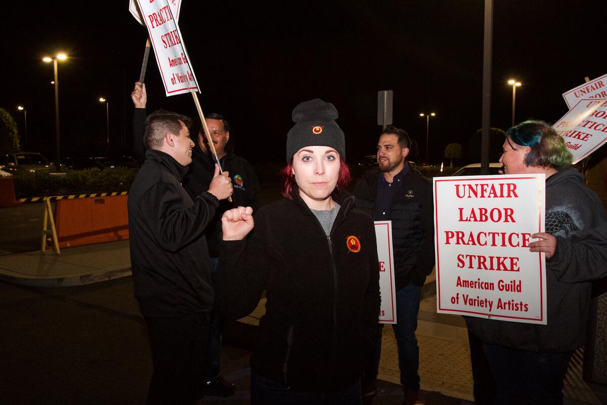 Erin Zapcic stands in front of fellow picketers; her right fist is raised in solidarity in the parking lot of Medieval Times.