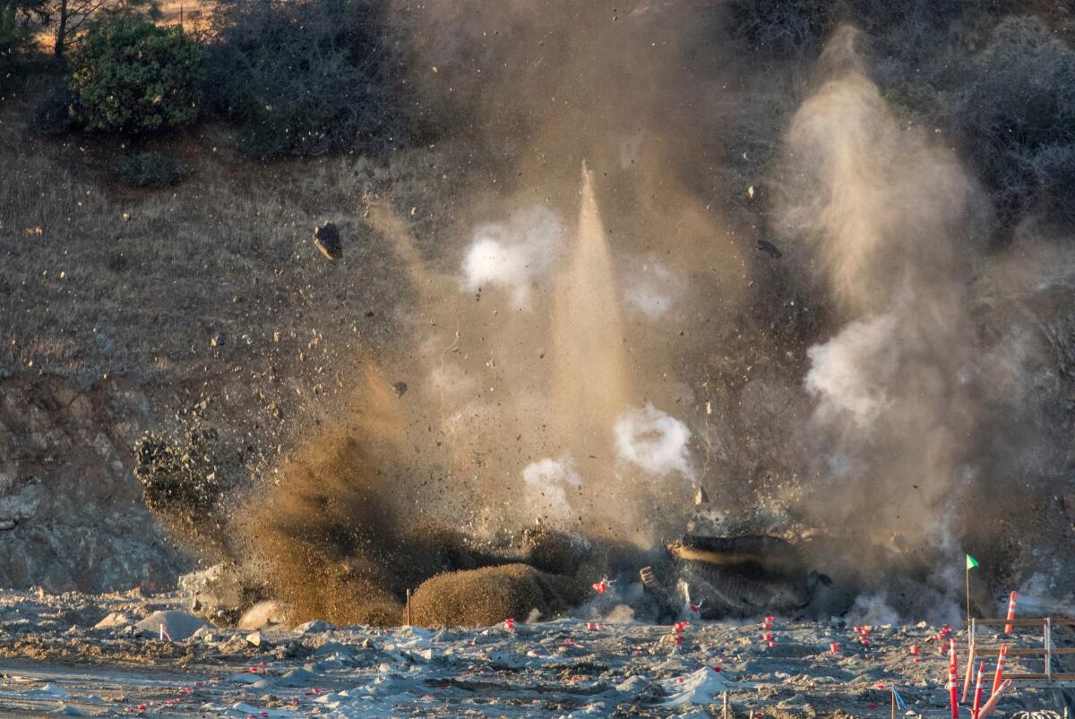 A controlled blast clears rock for the placement of the roller-compacted concrete splashpad downslope from the Lake Oroville emergency spillway on Tuesday.