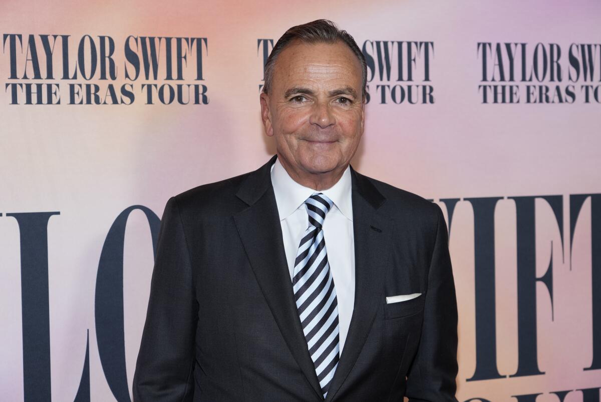 Rick Caruso smiles in a black suit and striped tie 