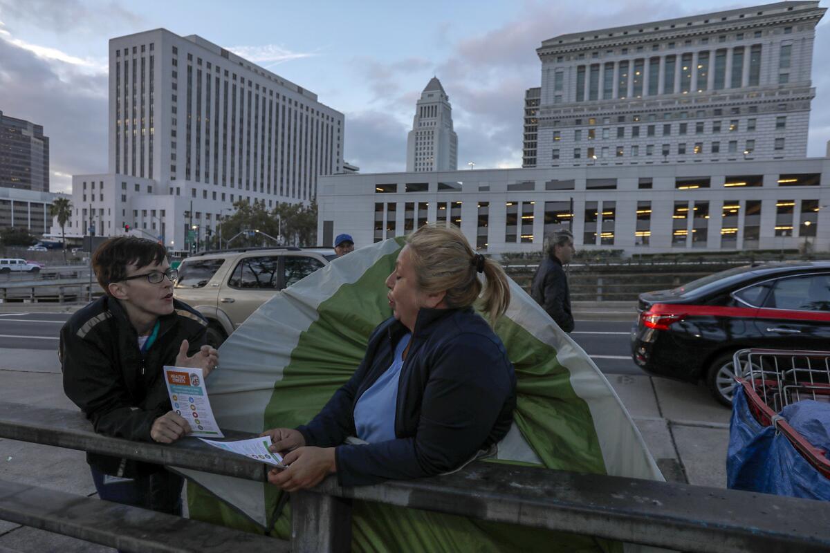 Amy Perkins of the Los Angeles Homeless Services Authority, left, explains new rules and restrictions to Leticia Cervantes, who lives in a tent.