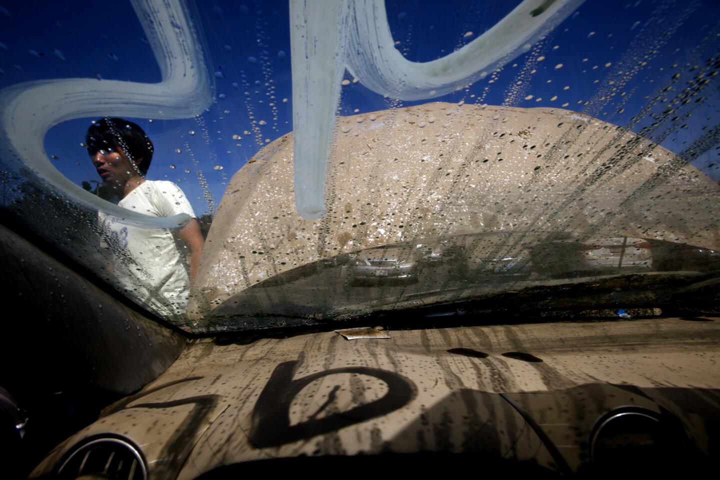 UCLA student Takeshi Shoji is seen through the flood damaged windshield of his car in a parking lot behind Jackie Robinson Stadium on Tuesday.