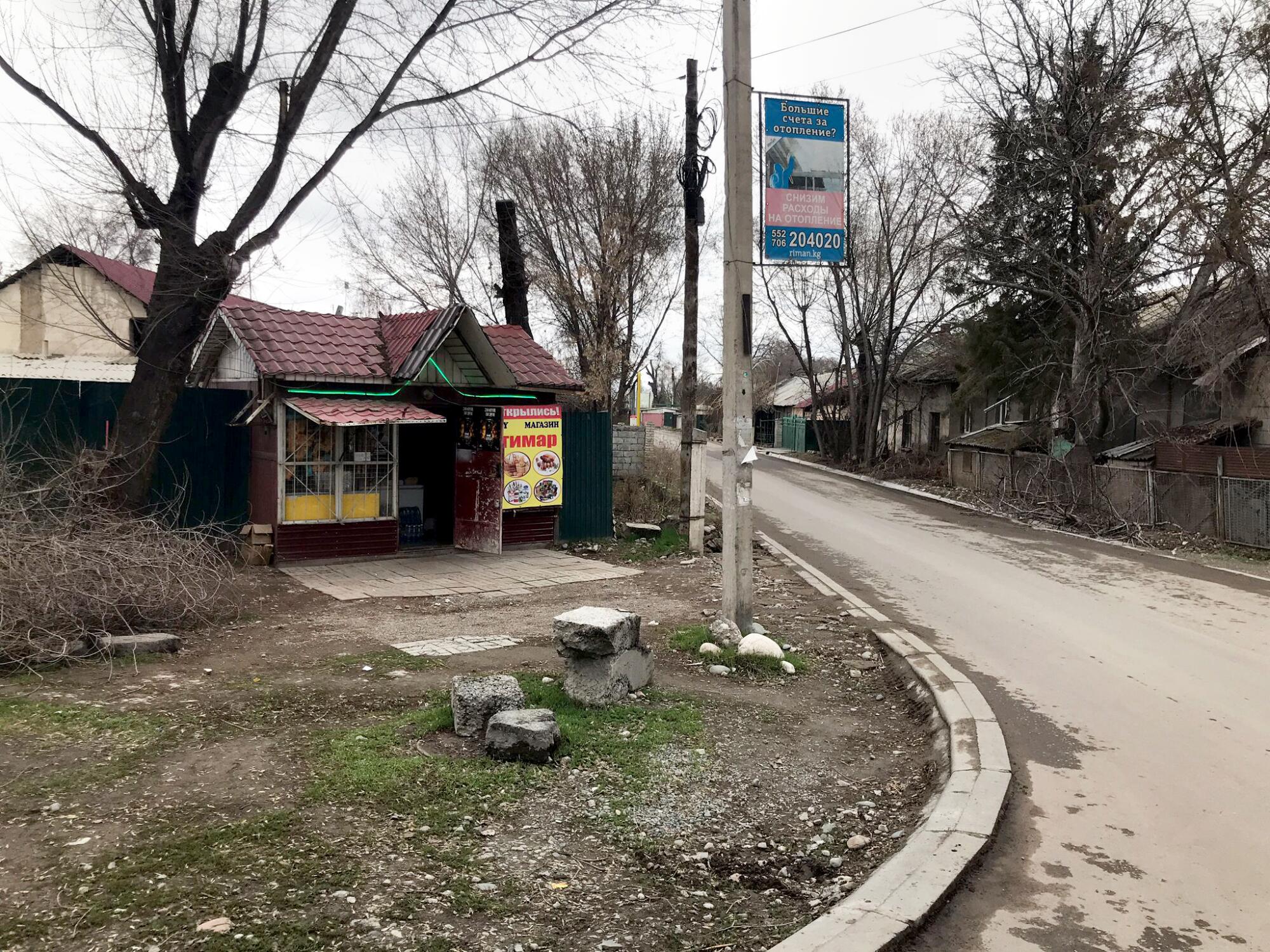 A view of a red-tiled building with a sign in front along a road, with other homes across the road.