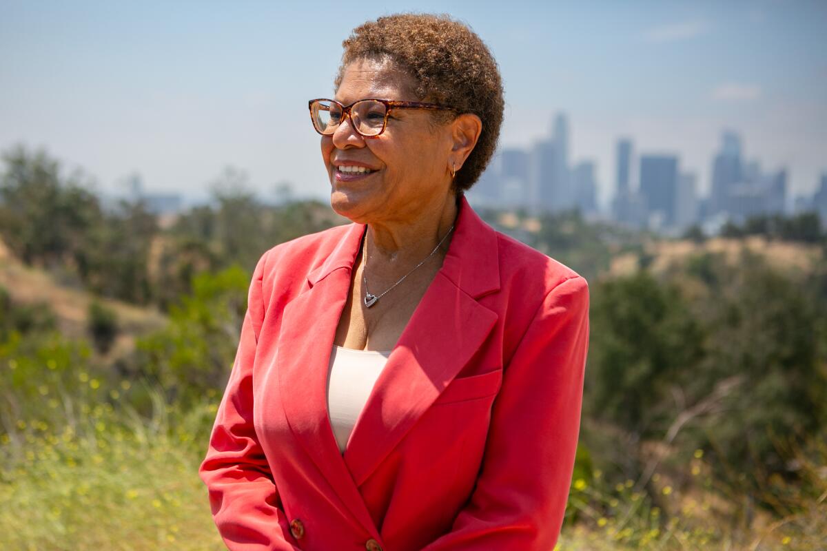 A woman in a red blazer, with a city behind her
