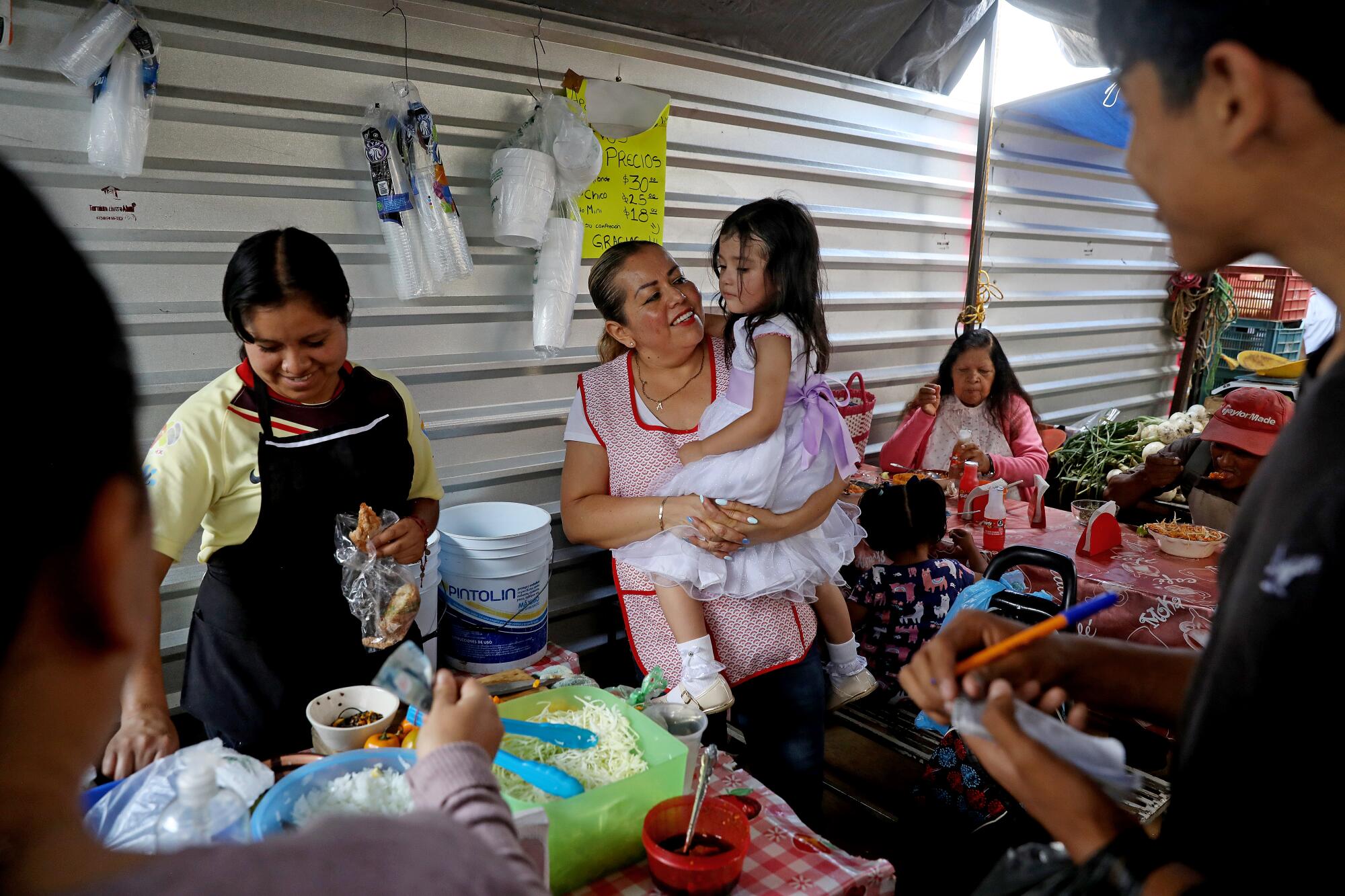 Josefina Rodriguez hoists granddaughter, Sofia, at her pozole at the town market in Pátzcuaro.