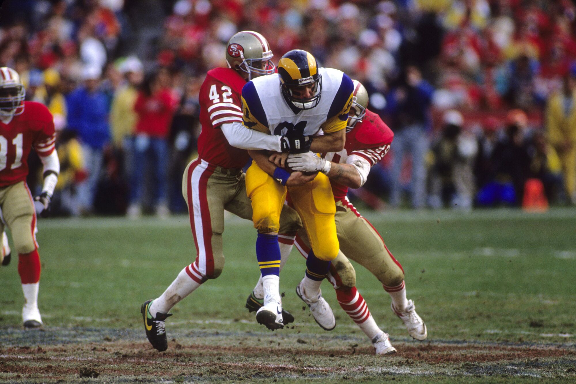Rams tight end Pete Holohan (81) is tackled by 49ers safety Ronnie Lott (42) and linebacker Mike Walter (99)