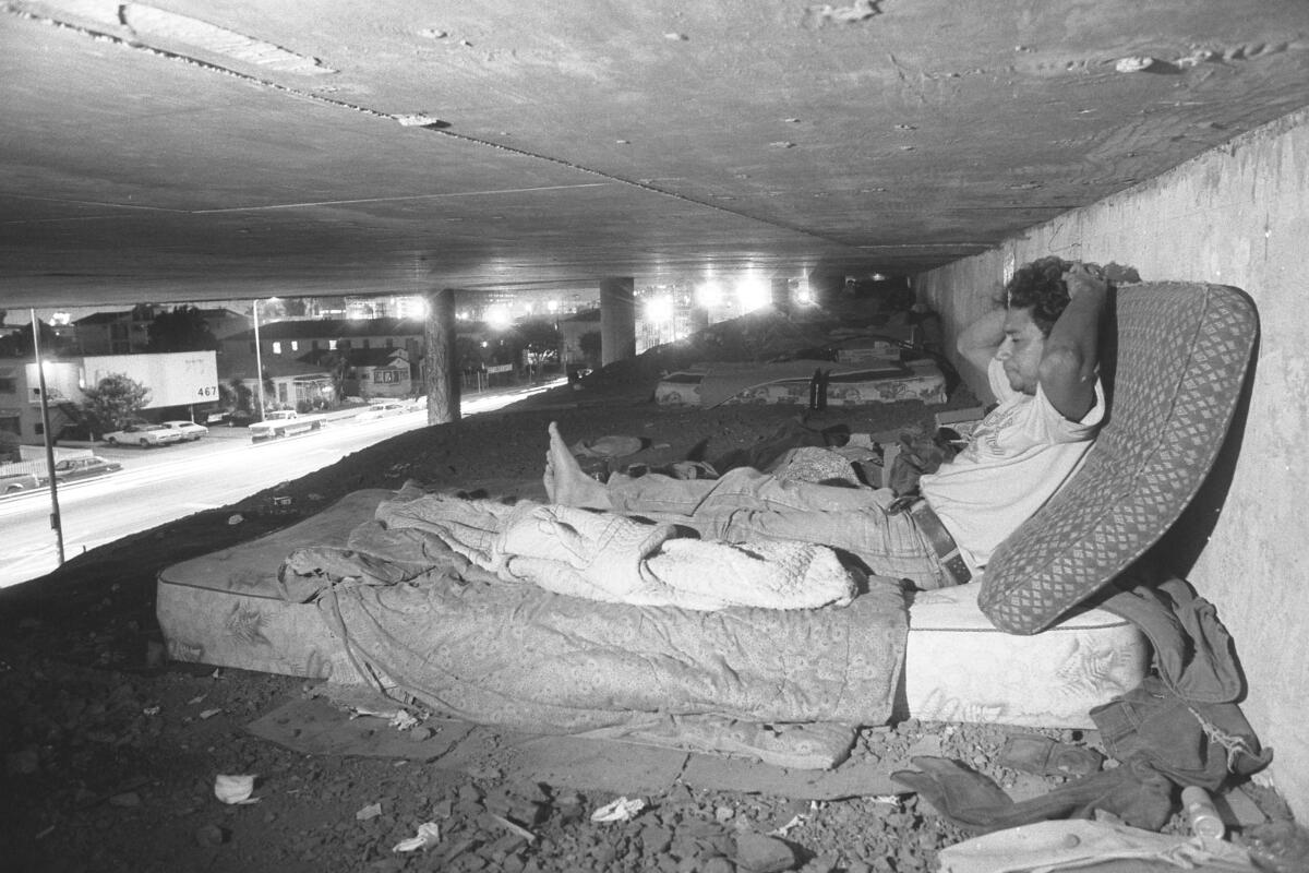 A man sits on a mattress under the freeway in Los Angeles in 1986.