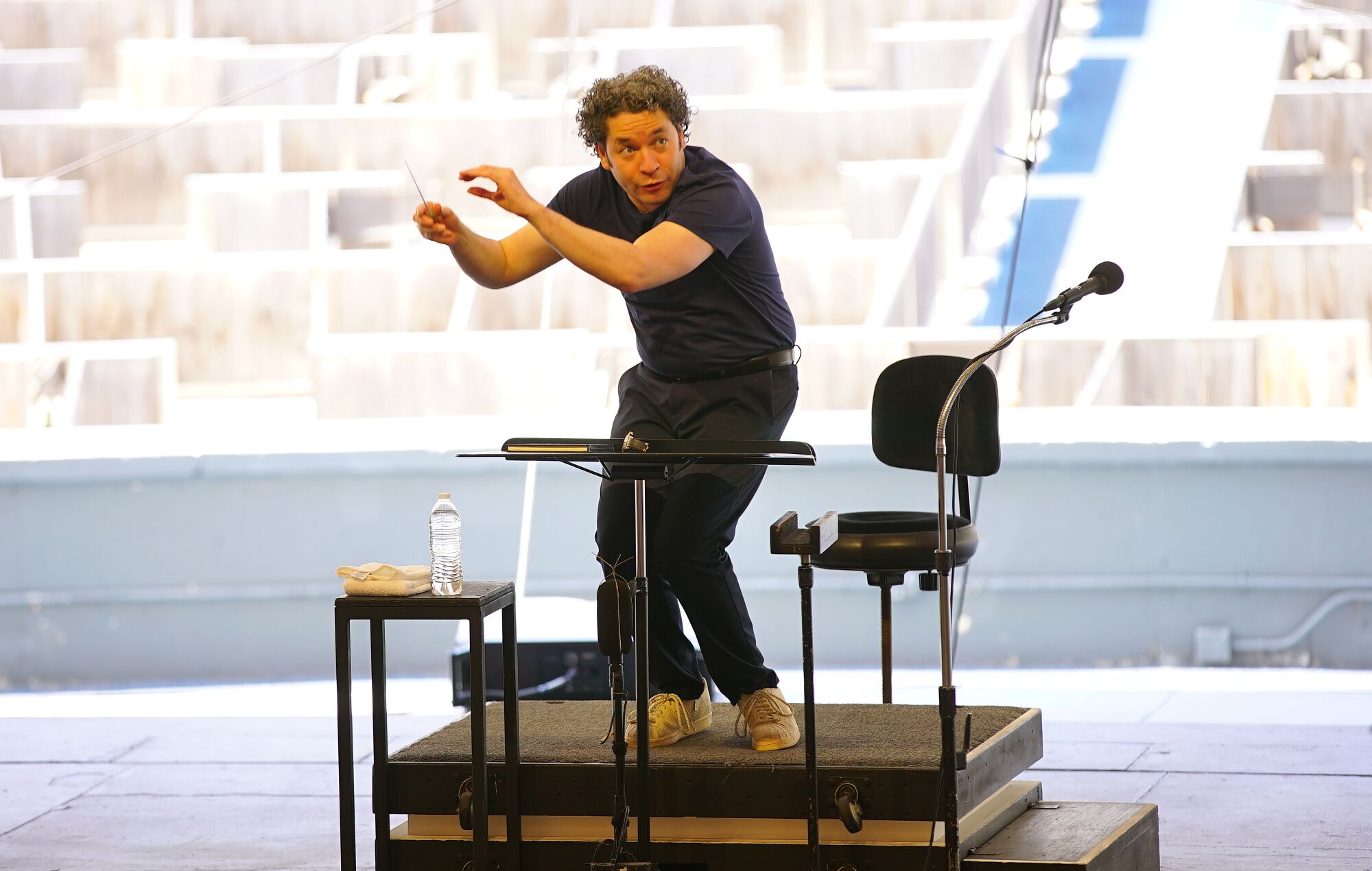 Dudamel conducts rehearsal with empty seats visible behind him