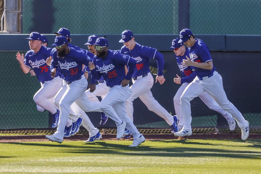 Dodgers players, including Shohei Ohtani, rear, run sprints in the outfield during the first day of spring training.