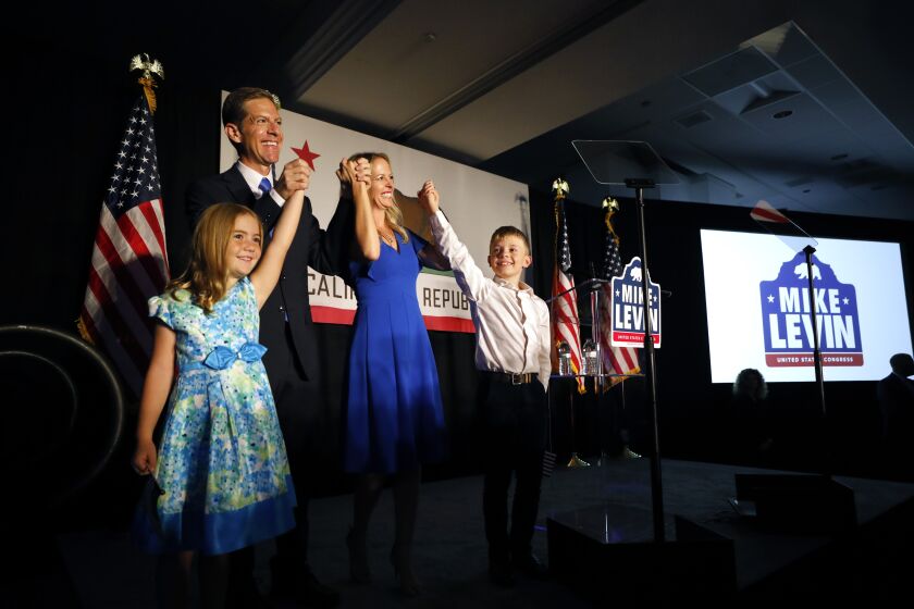 SAN DIEGO, CA - NOVEMBER 7: Rep. Mike Levin, center, with his wife Chrissy, daughter Elizabeth and son Jonathan cheer on a crowd at an election night celebration on Tuesday, November 8, 2022 in Del Mar, CA. (K.C. Alfred / The San Diego Union-Tribune)