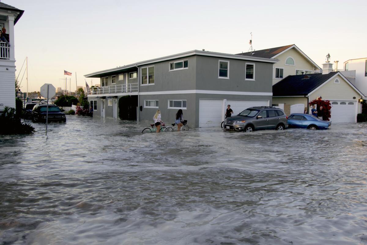 Streets in the Balboa Peninsula are flooded by coastal tides and high surf in Newport Beach on Friday.