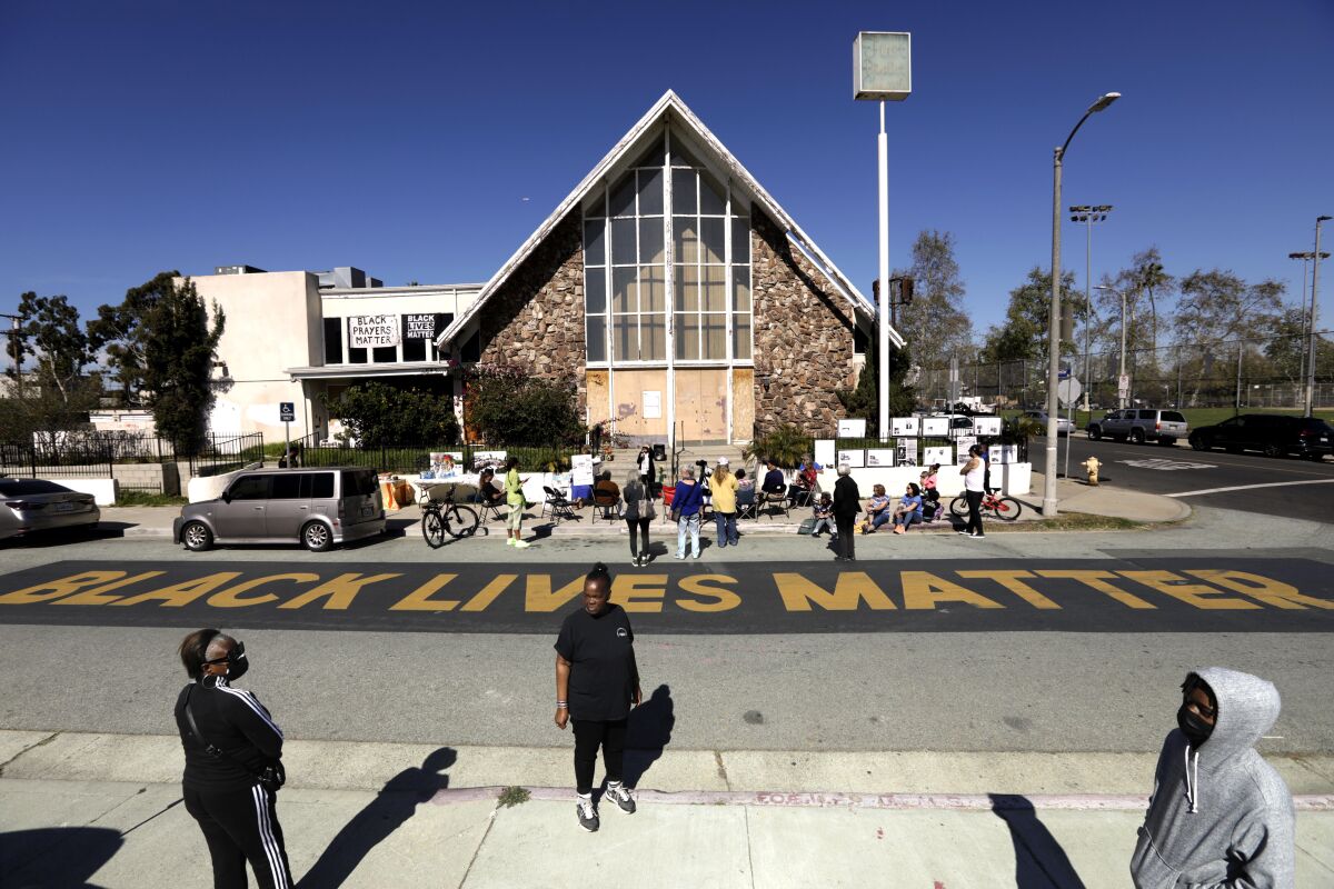 "Black Lives Matter" painted in block letters on the street in front of church building.