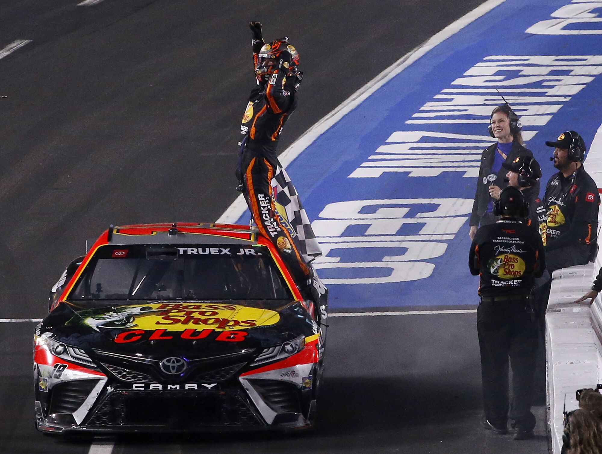 NASCAR driver Martin Truex Jr. stands on his car and raises his arms in triumph after winning the Clash at the Coliseum.