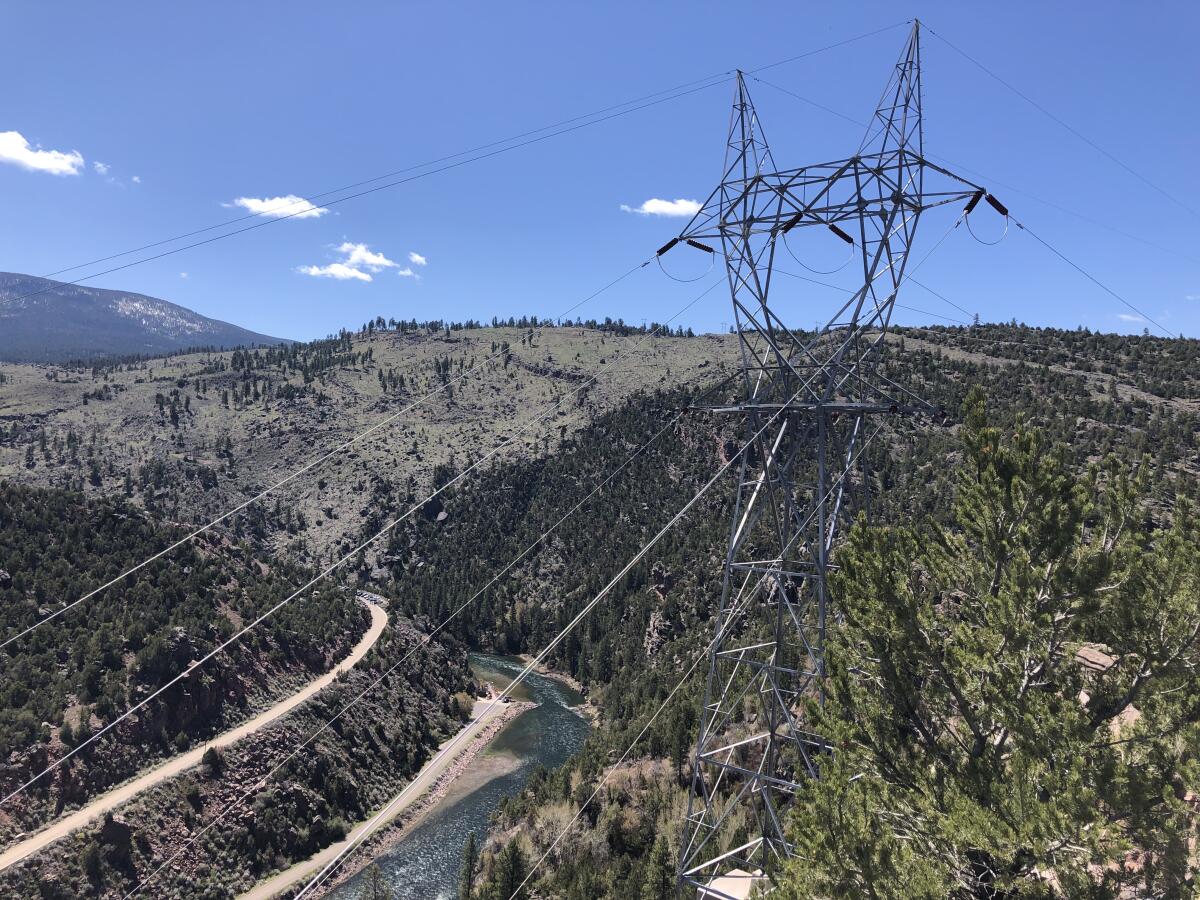 Electrical wires are seen above rolling hills bisected by a river.
