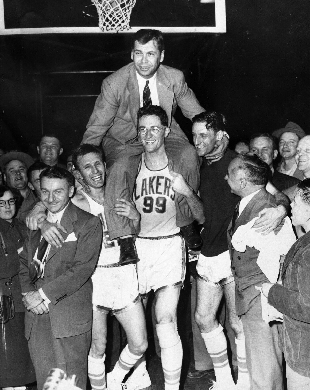 Minneapolis Lakers hoist coach John Kundla and carry him to their dressing room.