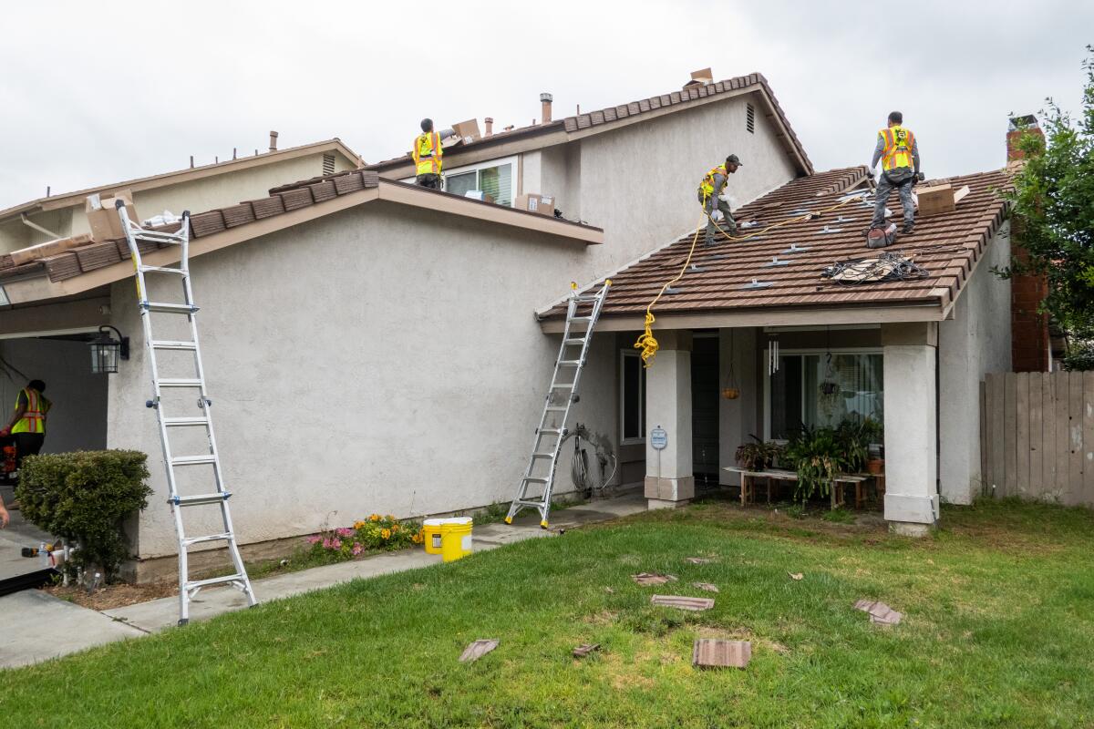 Workers from Solar Optimum install rooftop solar panels on a home in Brea in 2023.