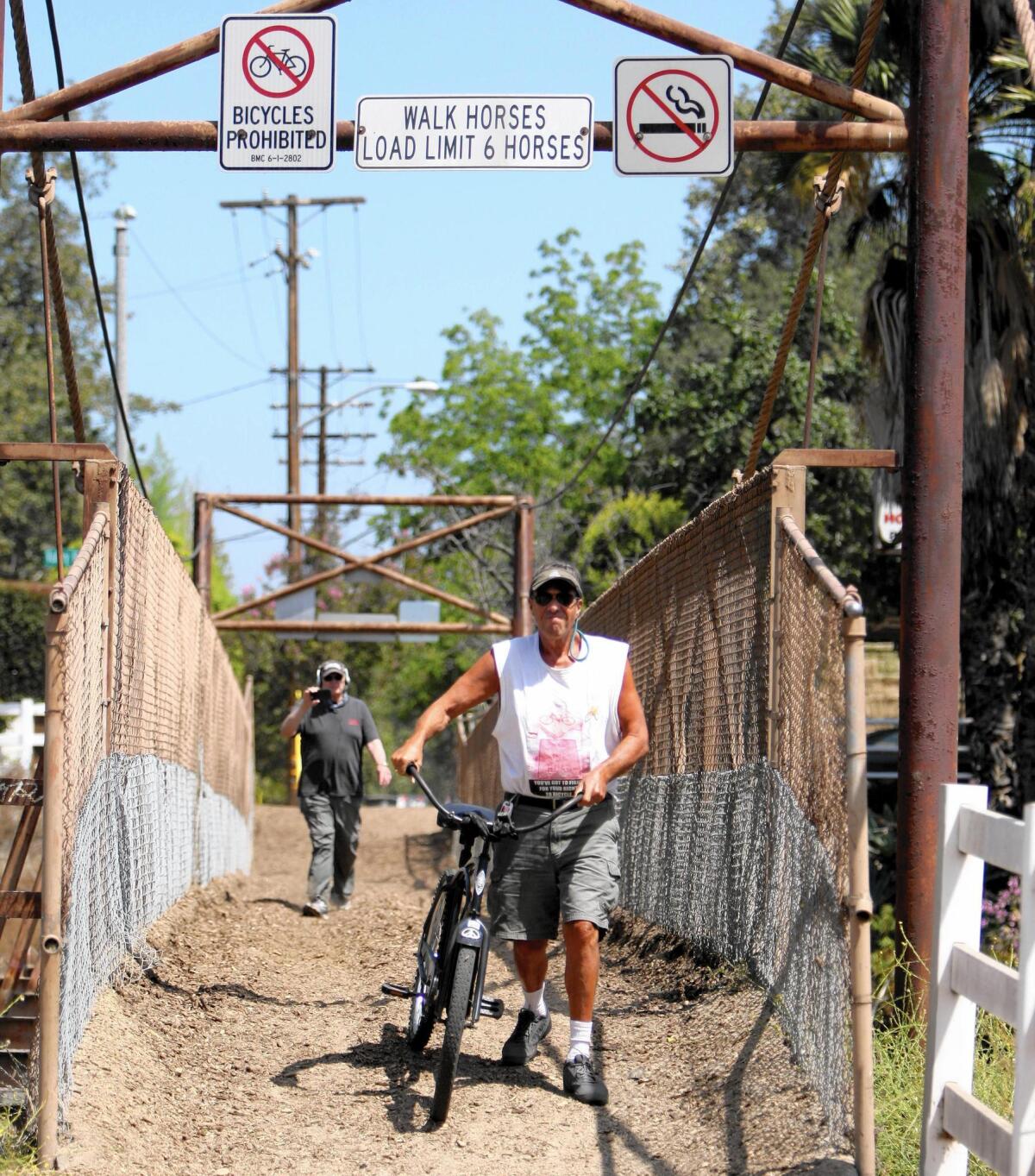 Burbank resident and cycling enthusiast Doug Weiskopf walks his bike across the Mariposa Street bridge in violation of a recent city ordinance.