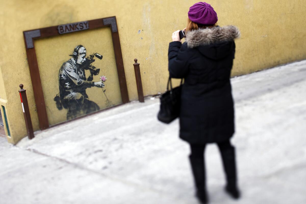 A passerby takes a picture of a Banksy piece in Park City, Utah in 2012.