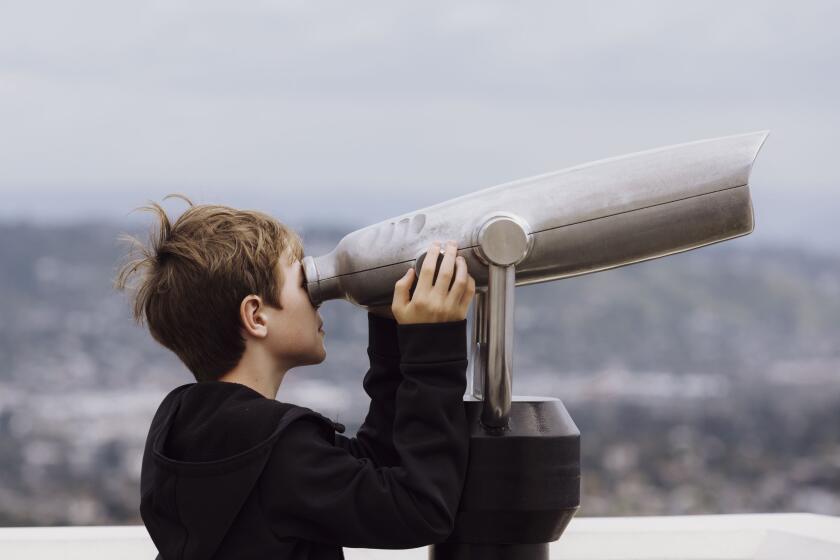Los Angeles, CA - March 15: Andrew Mackno, 10, looks into a pair of binoculars at the Griffith Observatory on Friday, March 15, 2024 in Los Angeles, CA. (Carlin Stiehl / For The Times)