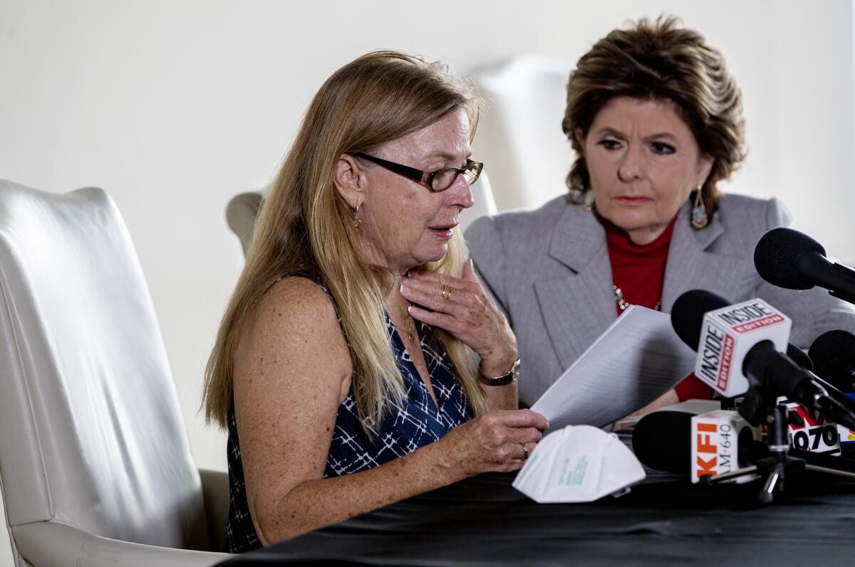 Two women sit behind a desk with microphones on it.