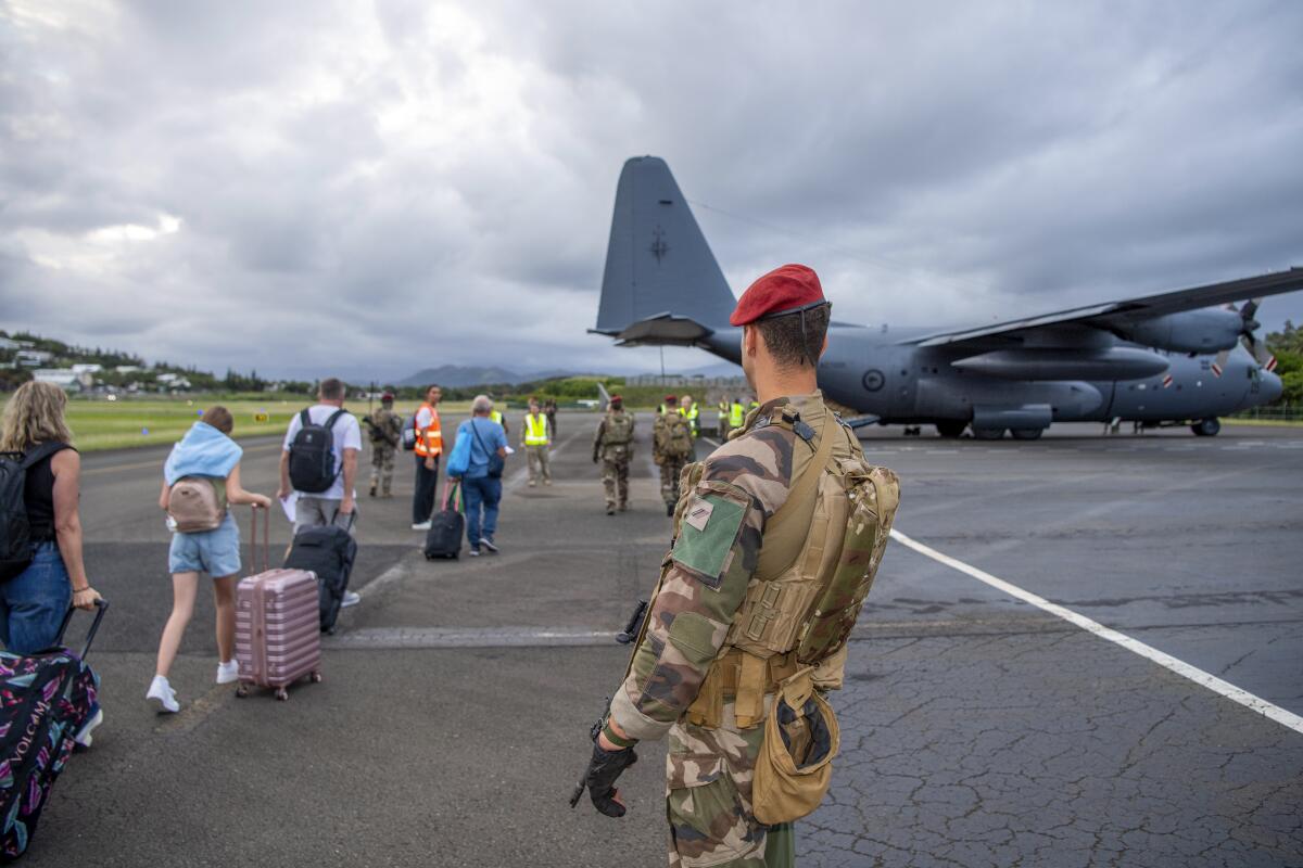 New Zealand tourists line up to board a New Zealand Defense Force aircraft at Magenta Airport in Noumea, New Caledonia