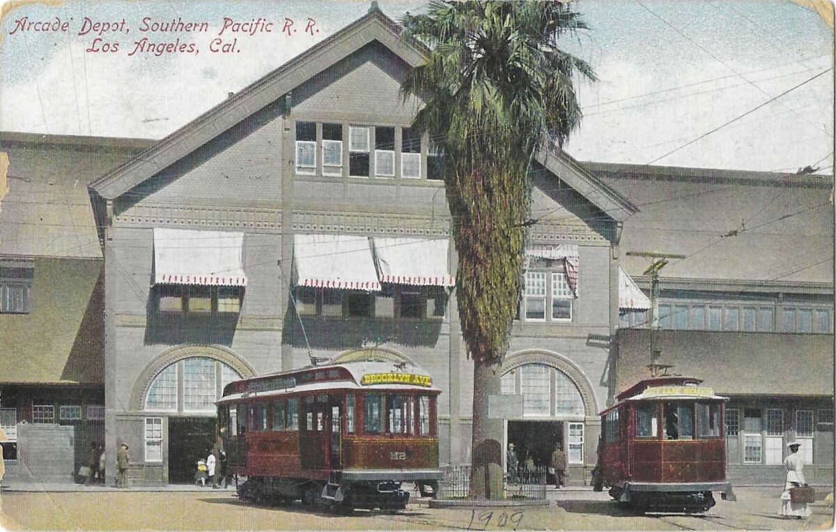 A pre-WWI vintage postcard shows two red cars outside the Southern Pacific Railroad's Arcade Depot