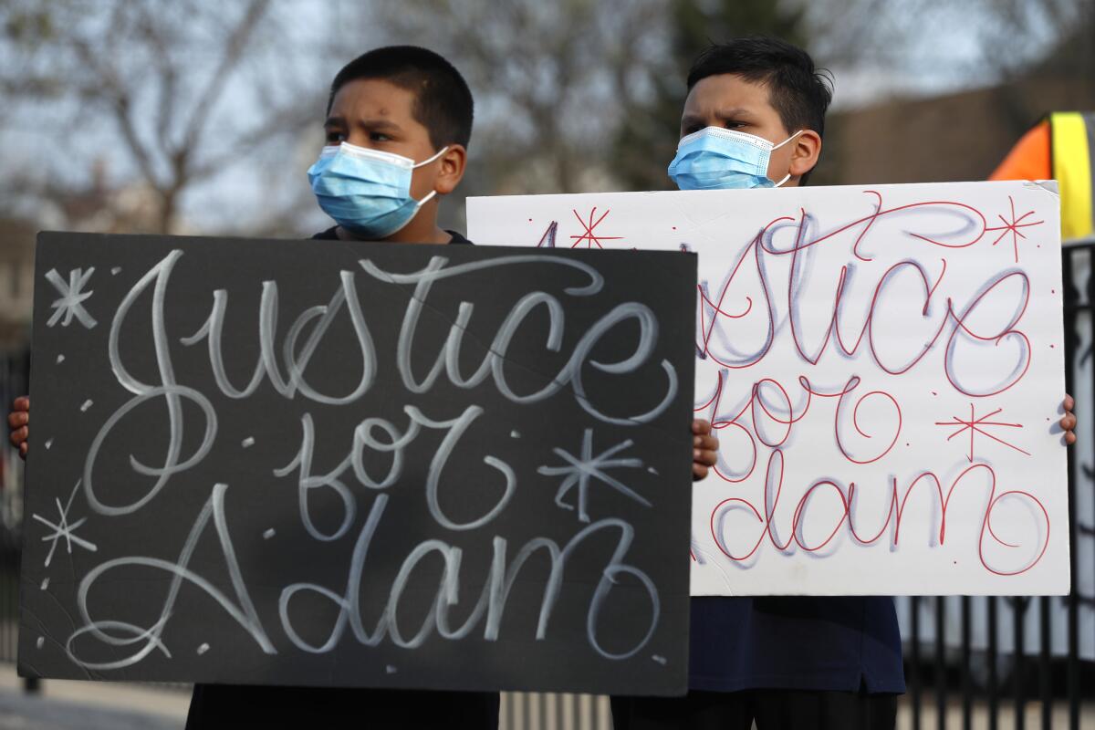 Jacob Perea, 7, left, and Juan Perea, 9, hold signs at an April 6 news conference after the death of 13-year-old Adam Toledo.