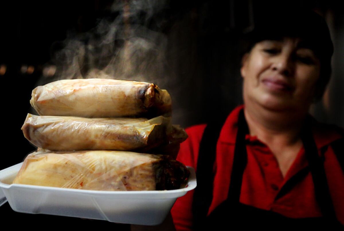 Maria Badajos delivers an order of red pork tamales in the kitchen at Juanito's in East Los Angeles.