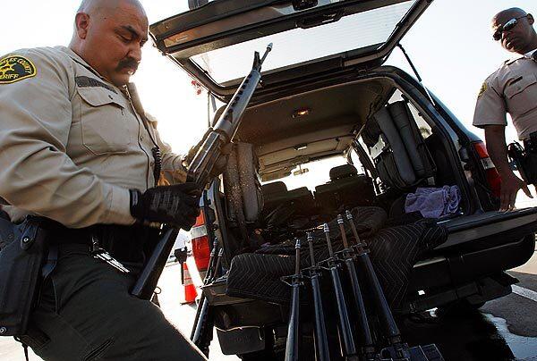 Los Angeles County sheriff's deputies inspect and inventory about a dozen civilian versions of military assault rifles during the annual "gift for guns" exchange program in Compton. One man turned in dozens of weapons.
