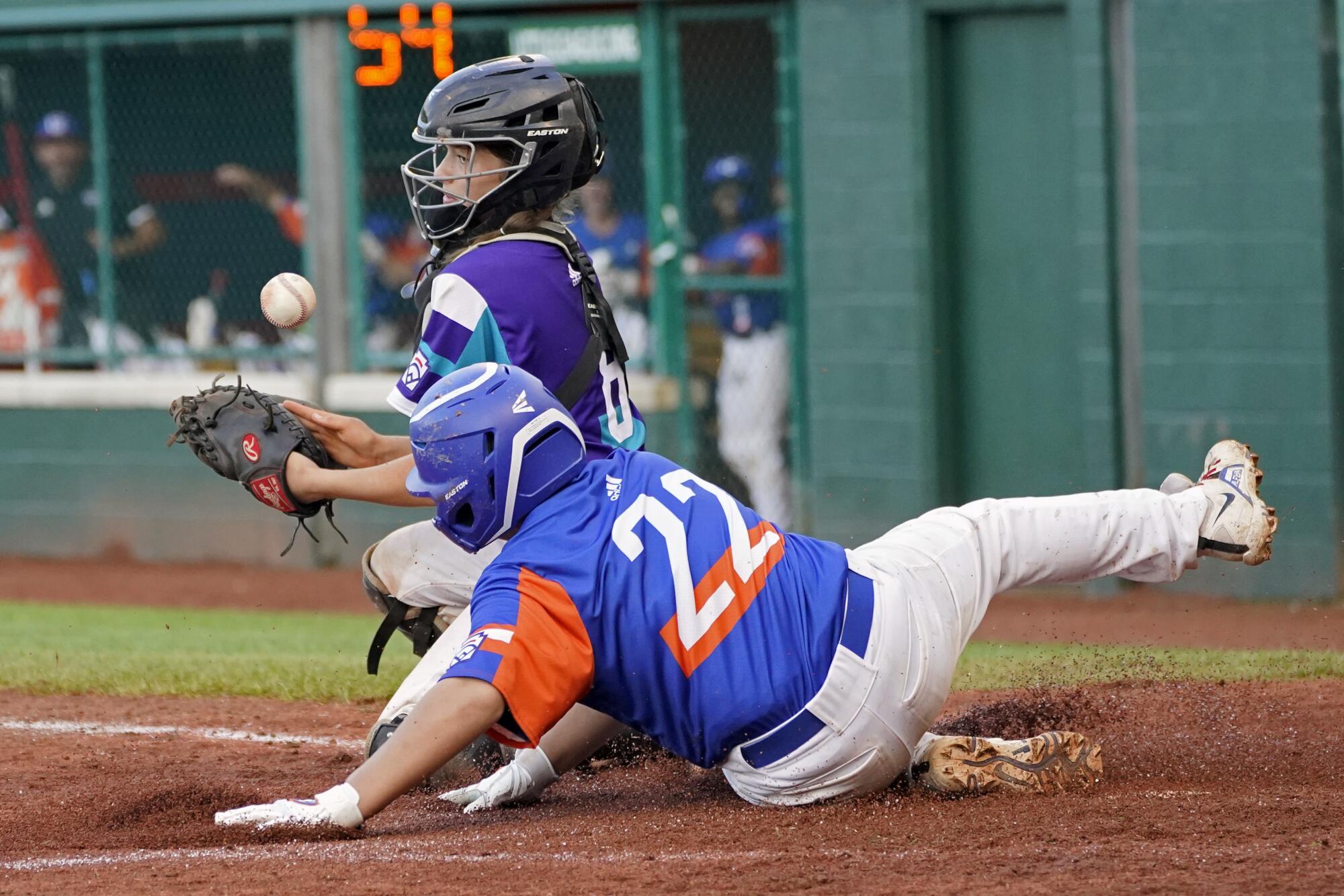 Taylor, Mich.'s Jackson Surma (22) scores as the ball gets past Abilene, Texas, catcher Ella Bruning (8).