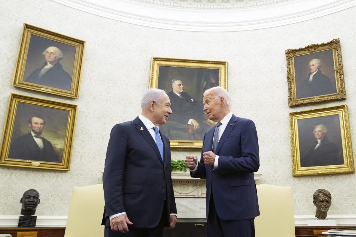 President Biden talks with Israeli Prime Minister Benjamin Netanyahu with presidential portraits on the wall behind them.