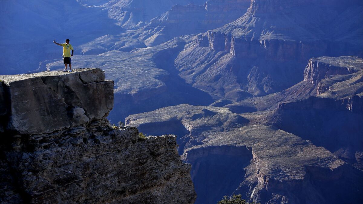 A tourist takes a "selfie" photograph on a cliff located above the Grand Canyon in Grand Canyon, Ariz. on June 27, 2014.