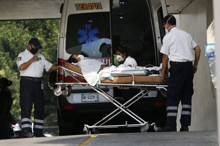 Medical workers wearing masks against the spread of the new coronavirus bring in a patient in respiratory distress by ambulance to the Parque de Los Venados hospital in Mexico City, Wednesday, May 20, 2020. (AP Photo/Marco Ugarte)