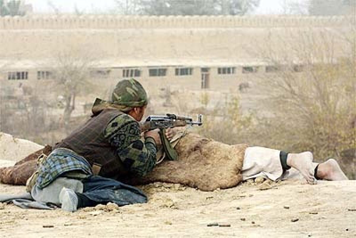 A Northern Alliance fighter seeks cover behind a corpse during battle at a fortress in Qala-i-Jangy. The last 150 Taliban holdouts there were killed, according to an Afghan security official.