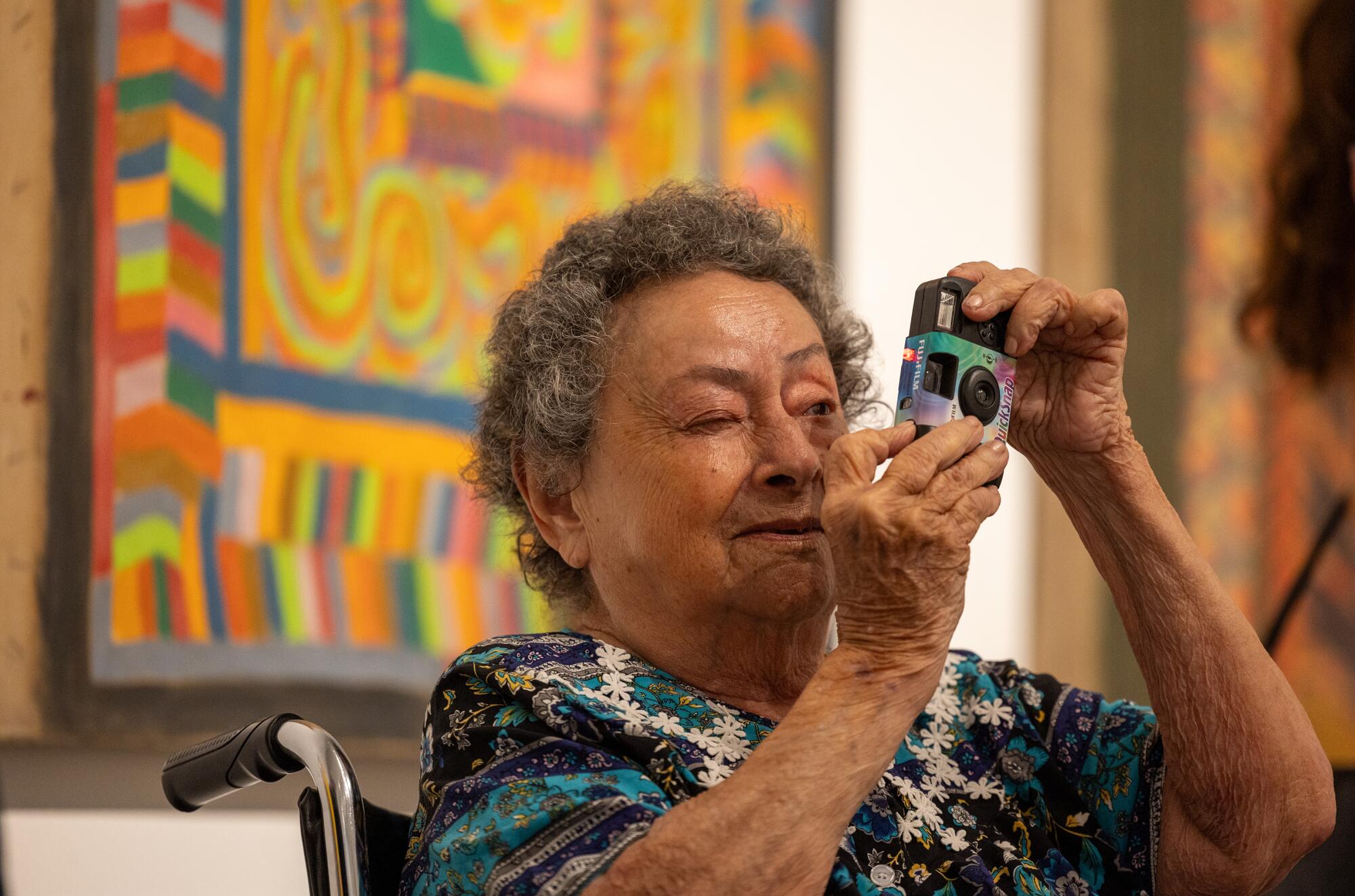 A woman takes a photo of her LACMA show with a disposable film camera. 