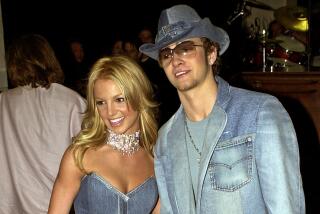 Britney Spears in a denim gown standing next to Justin Timberlake in a denim suit, wide-brimmed hat and sunglasses