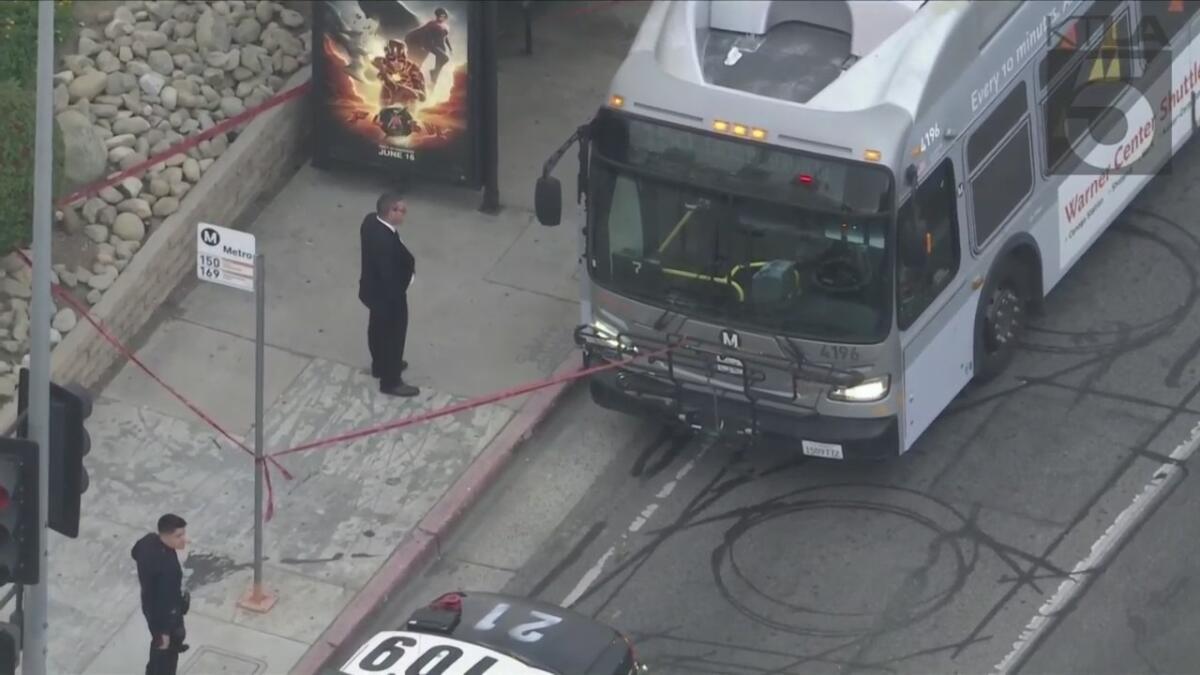 Two men stand near an L.A. Metro bus.